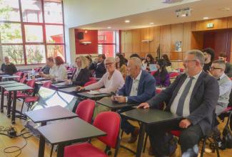 Personnes assises qui assistent à une présentation dans la salle des colloques. Au premier plans les présidents de l'ULCO et l'UPJV et la présidente de l'université d'Artois
