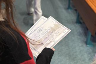 Photo : plan rapproché sur le certificat des cordées de la réussite dans les mains d'un étudiant