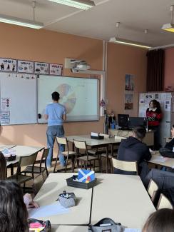 Salle de cours - un élève au tableau - des tables rassemblées pour des ateliers en groupes d'élèves
