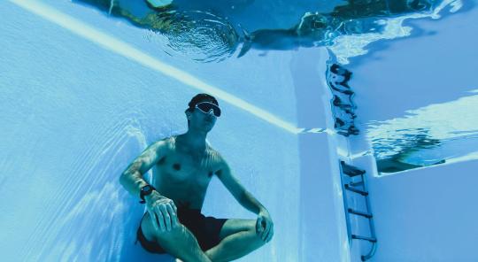 Homme en apnée assis au fin d'une piscine