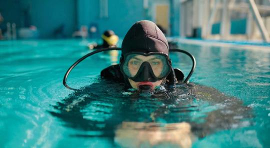 Personne dans une piscine couverte en combinaison de plongée avec un masque de plongée